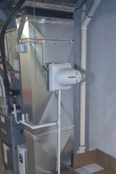 Mechanical equipment in a utility room with ductwork, pipes, and a white wall-mounted unit on the right. Mechanical equipment in a utility room with ductwork, pipes, and a white wall-mounted unit on the right.