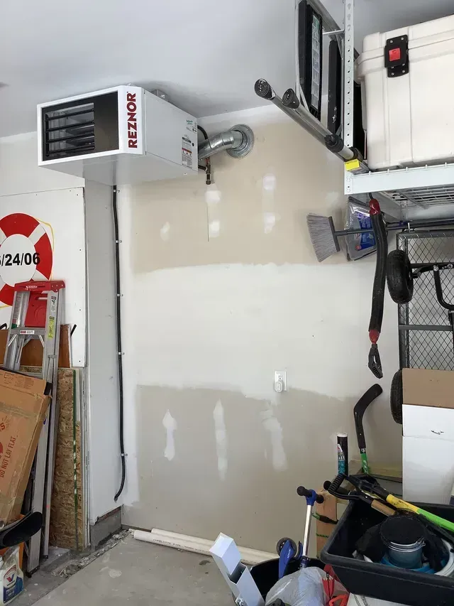 A reznor heater is mounted to the wall of a garage