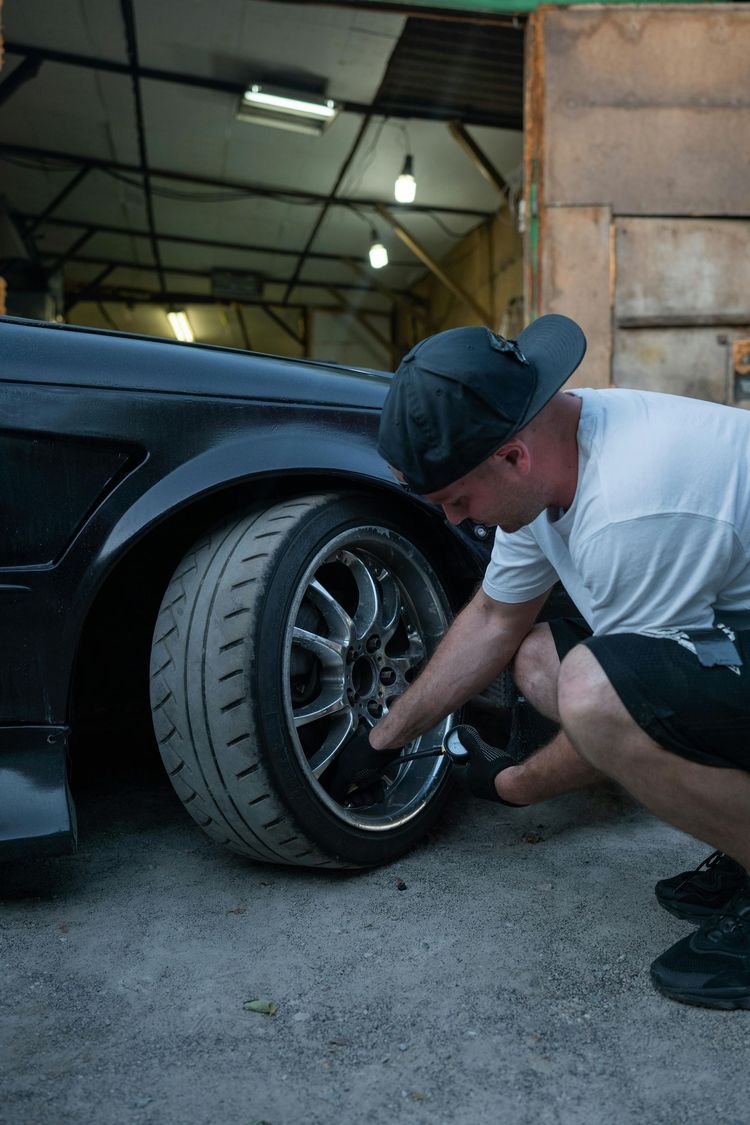 A man is changing a tire on a car in a garage.