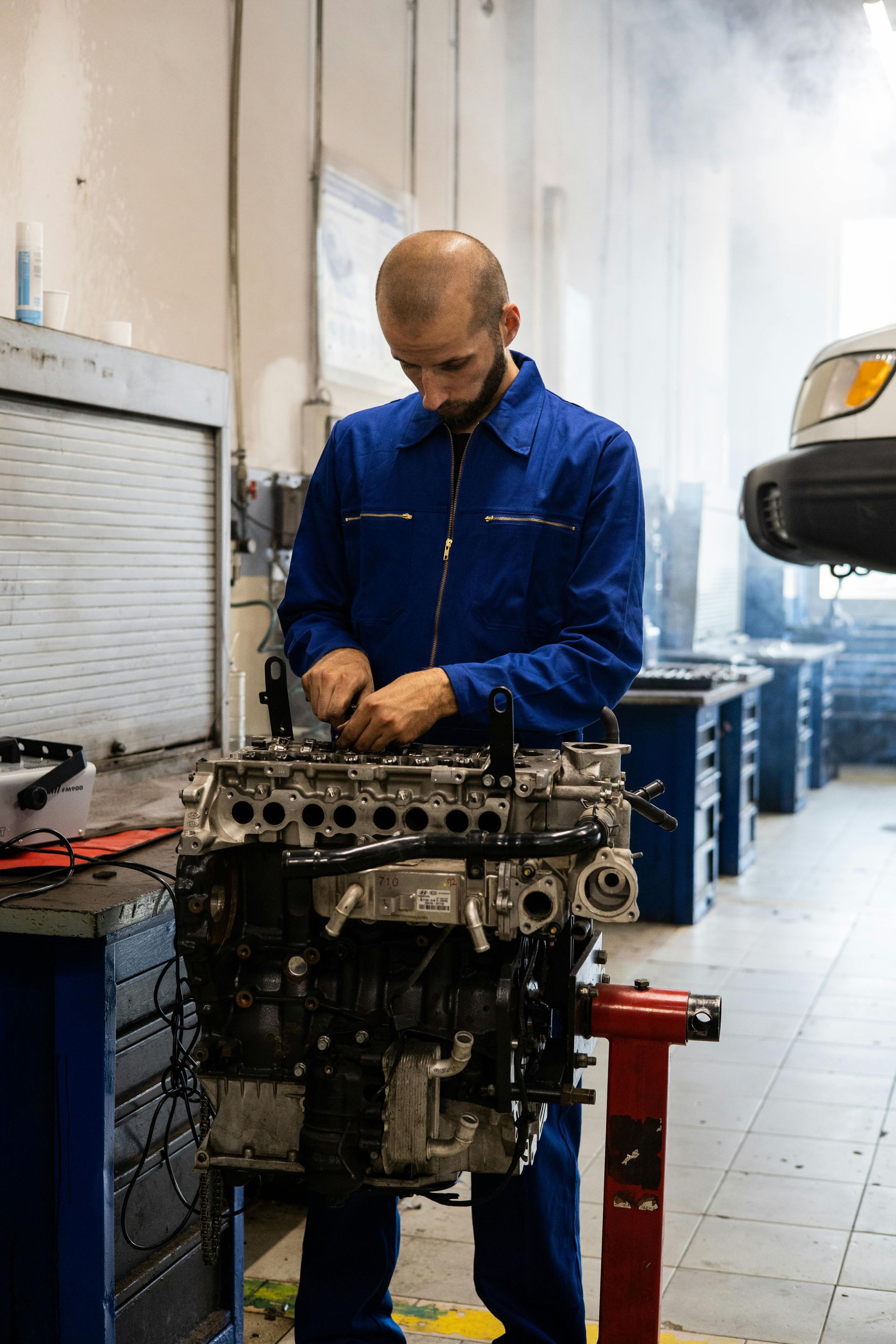 A man is working on a car engine in a garage.