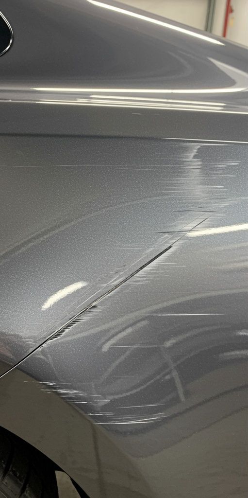 A close up of a silver car with a scratch on the side.