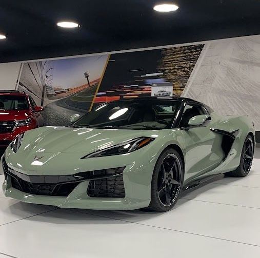 A green sports car is parked in a showroom.