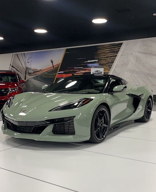 A green corvette is parked in a showroom.