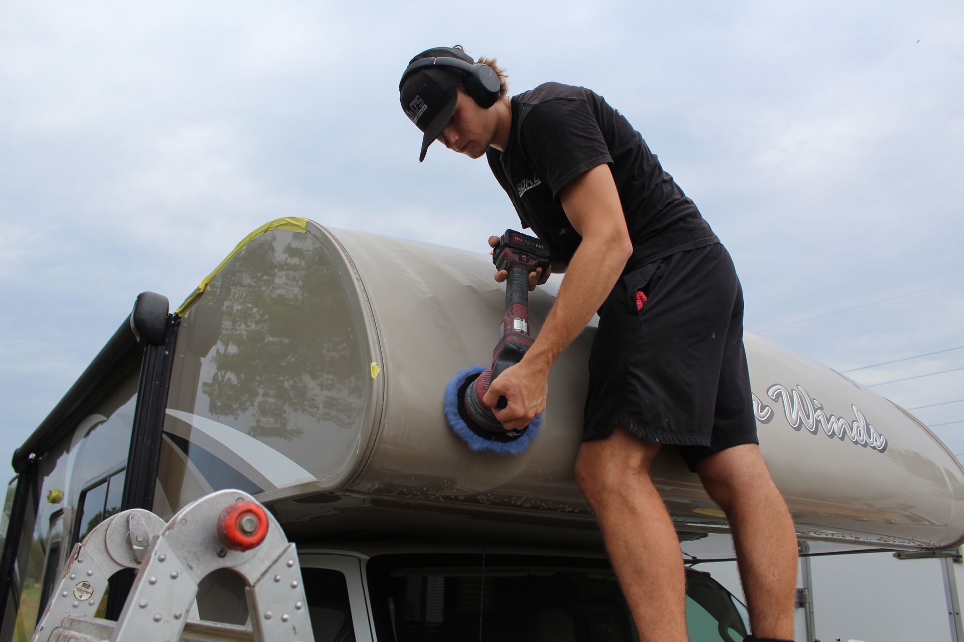 A man is polishing a black car with a machine.