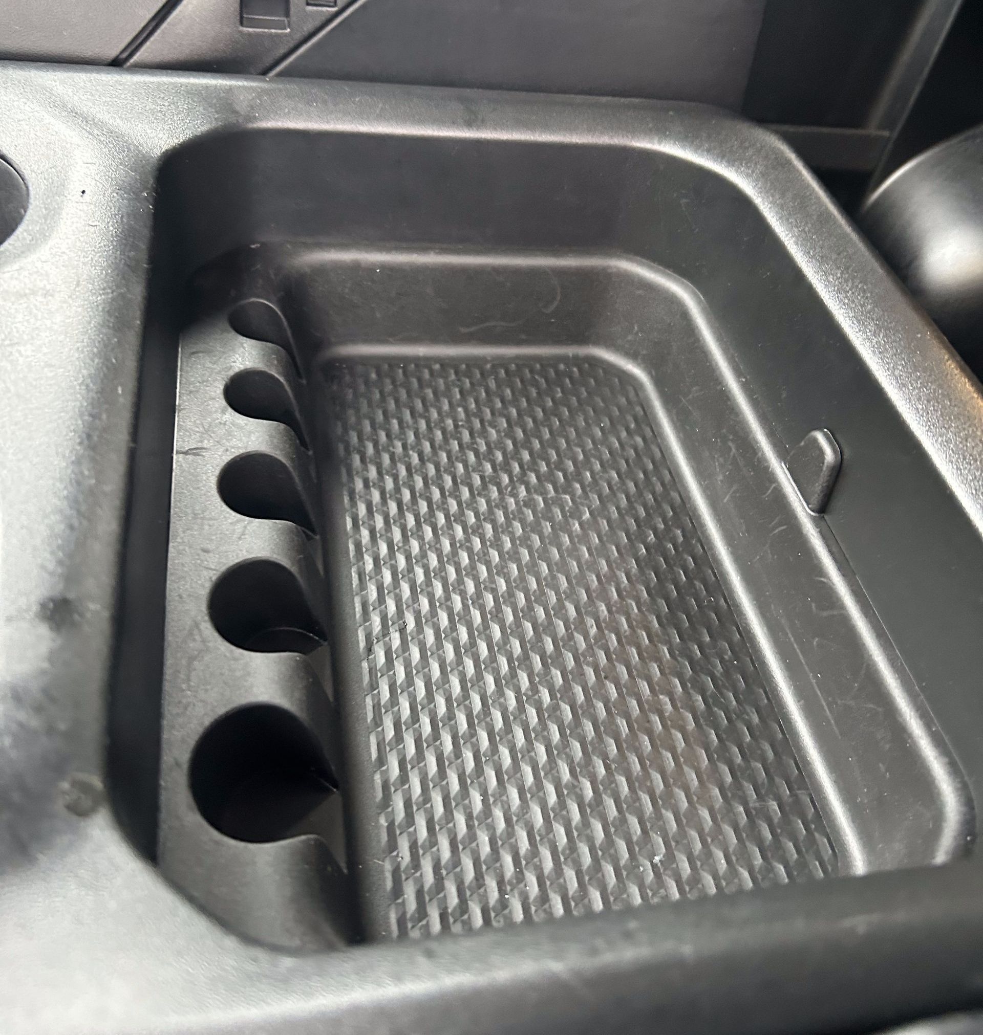 Car console tray with cupholders and textured bottom.