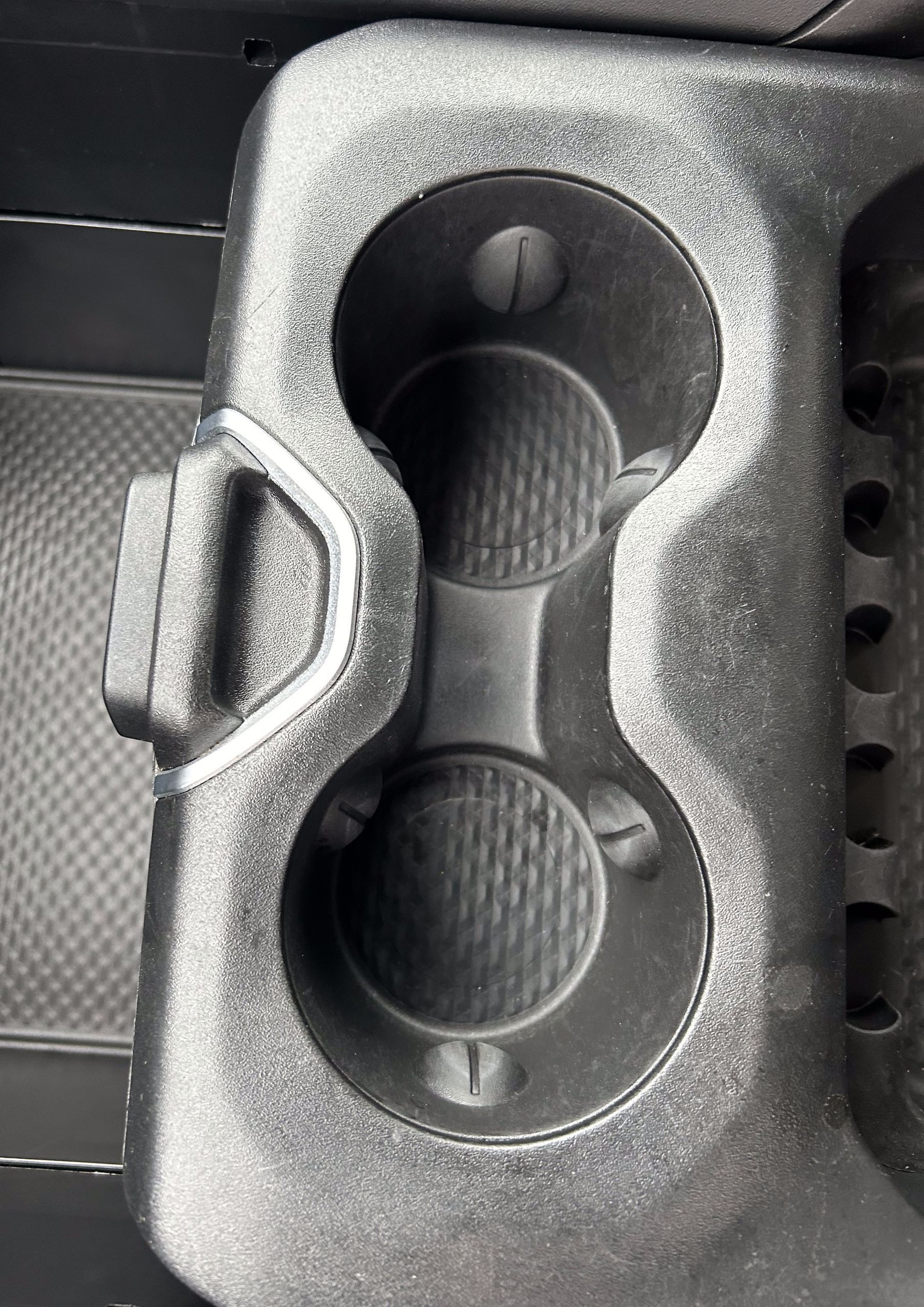 Black car cup holders with textured bottoms and a side latch.