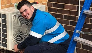 Smiling Men Electrical Repairing The Air Conditioner — John B Electrical In Wooragee VIC
