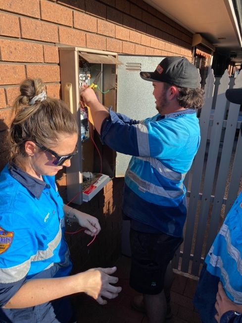Electrician With Gloves Measures The Voltage Of A Residential Electrical System — John B Electrical In Wooragee VIC