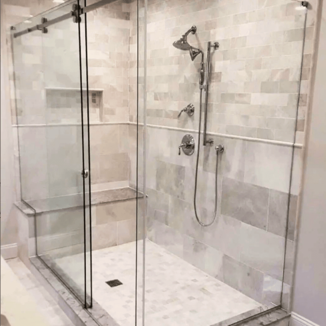 A bathroom with a walk in shower with sliding glass doors and a shower head.