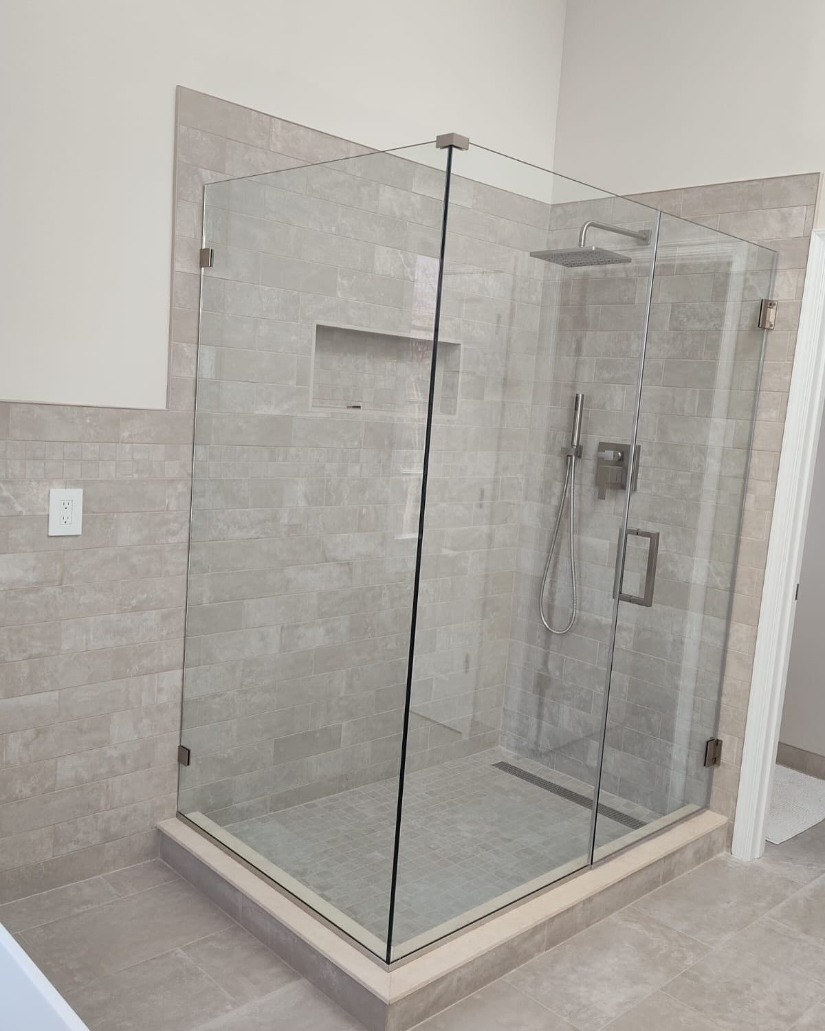 A bathroom with a walk in shower with a glass door.