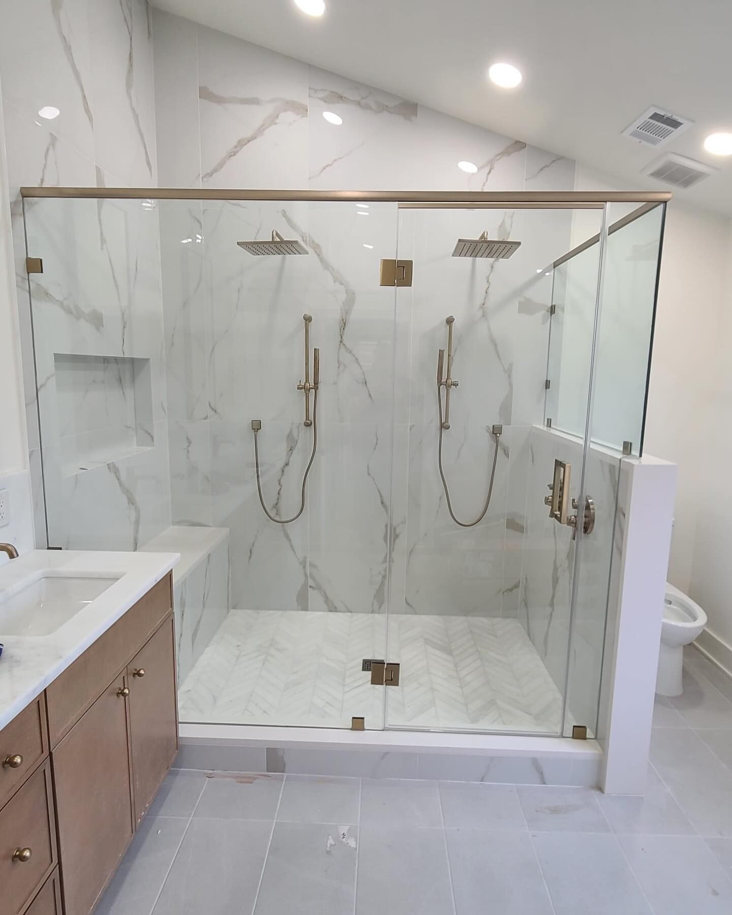 A bathroom with two showers , a sink and a toilet.