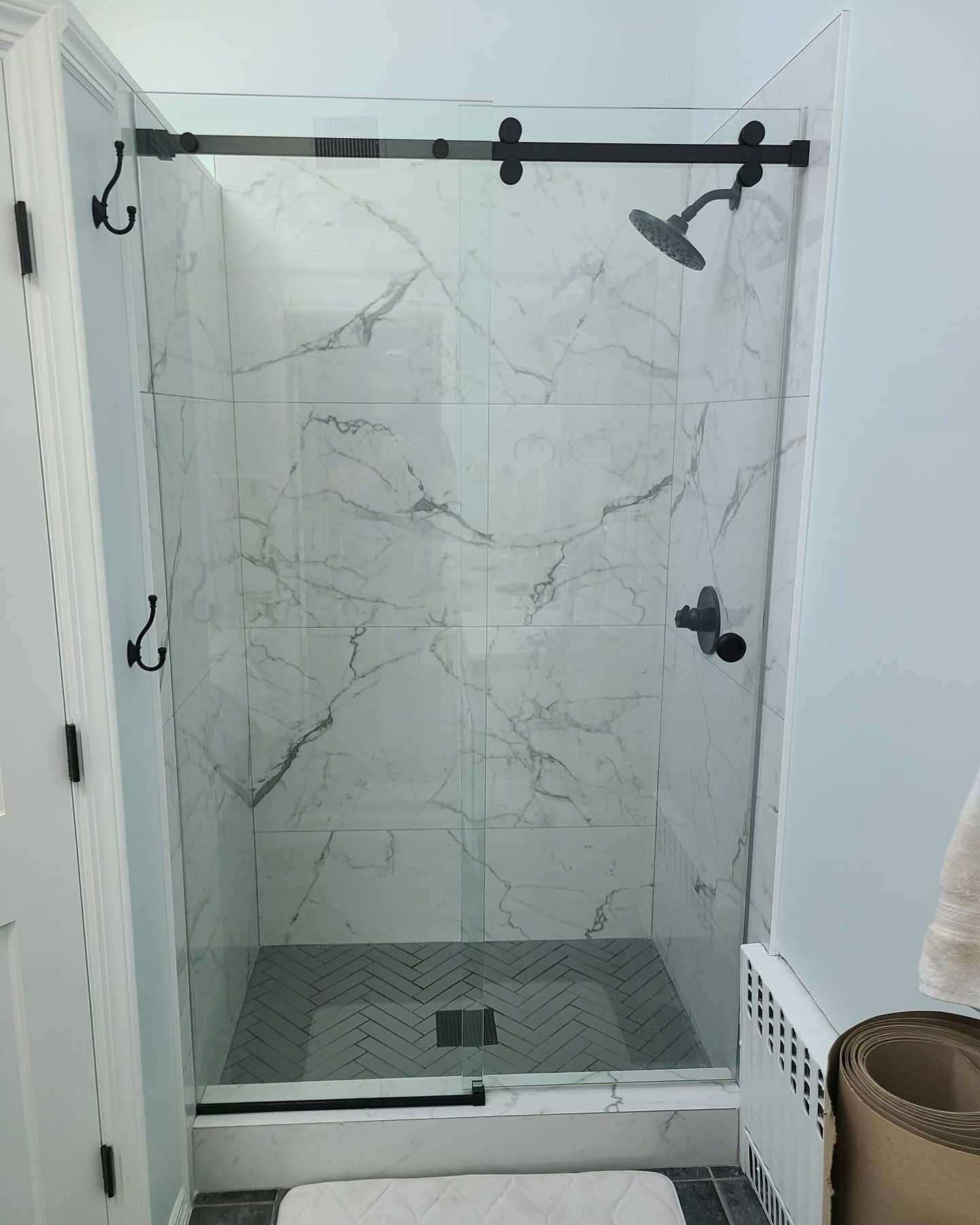 A bathroom with a shower stall with a sliding glass door.