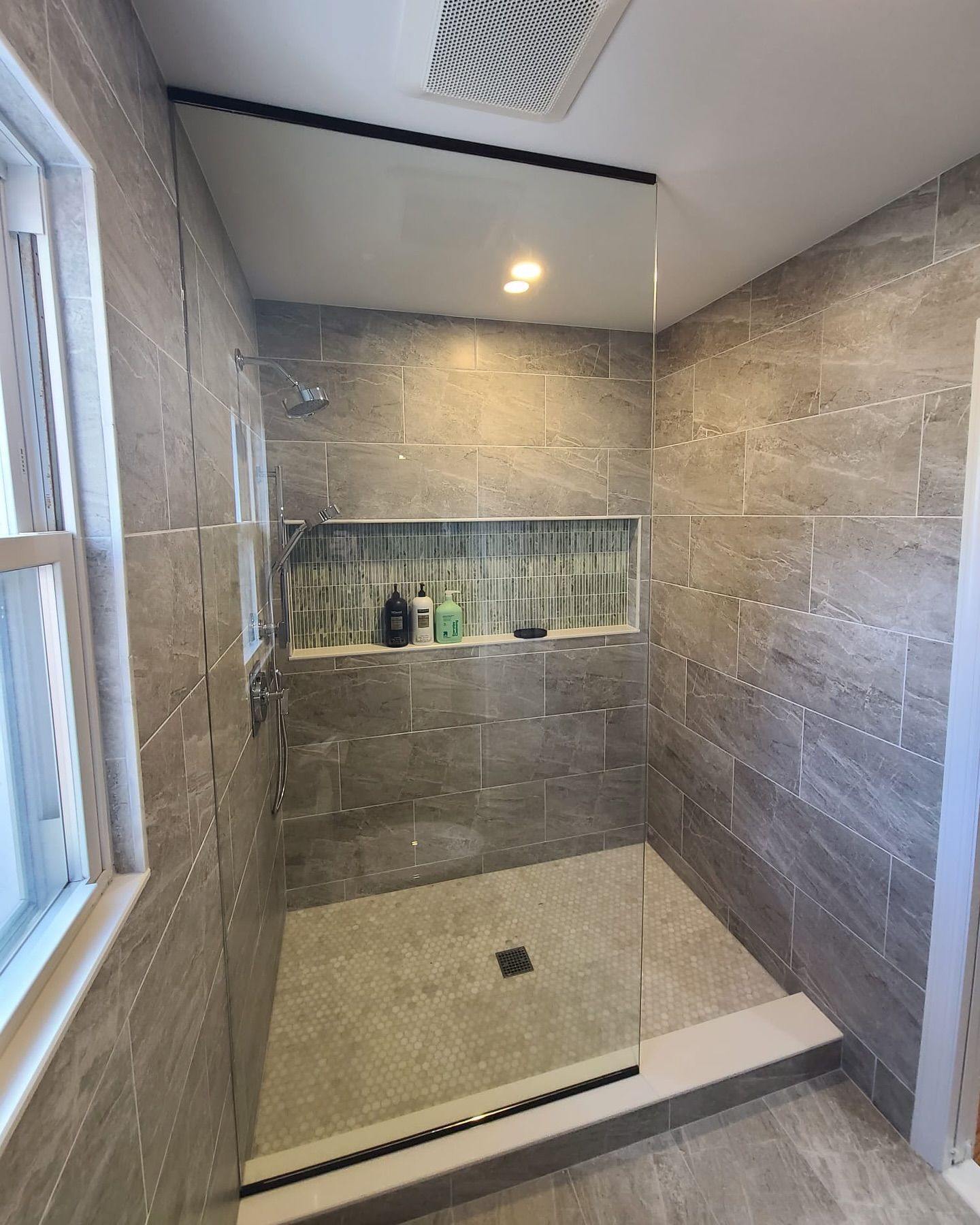 A bathroom with a walk in shower and a window.