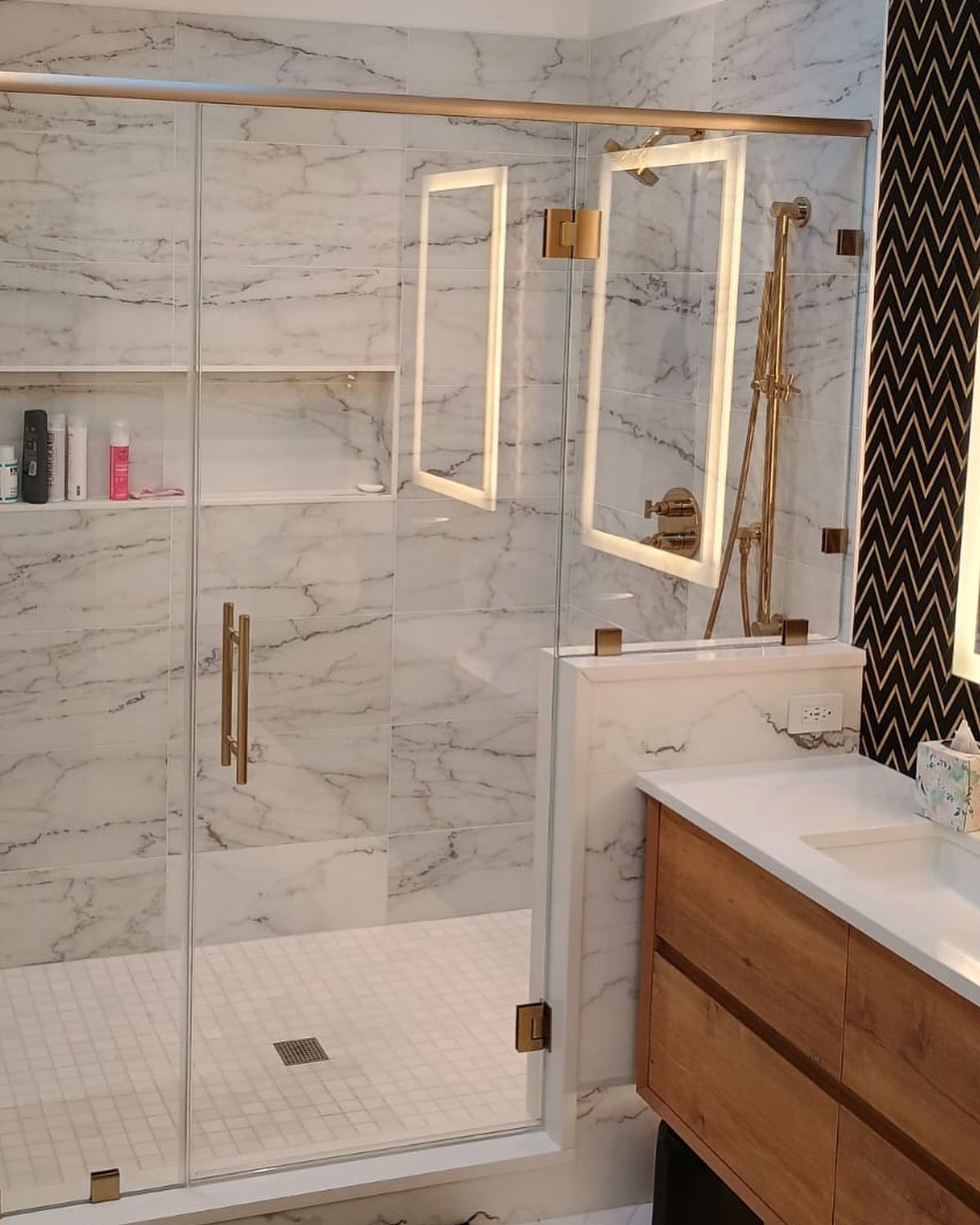 A bathroom with marble walls and a sliding glass shower door