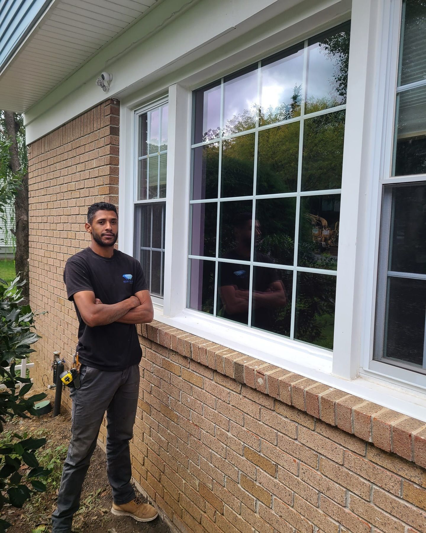 A man is standing in front of a window on a brick building.