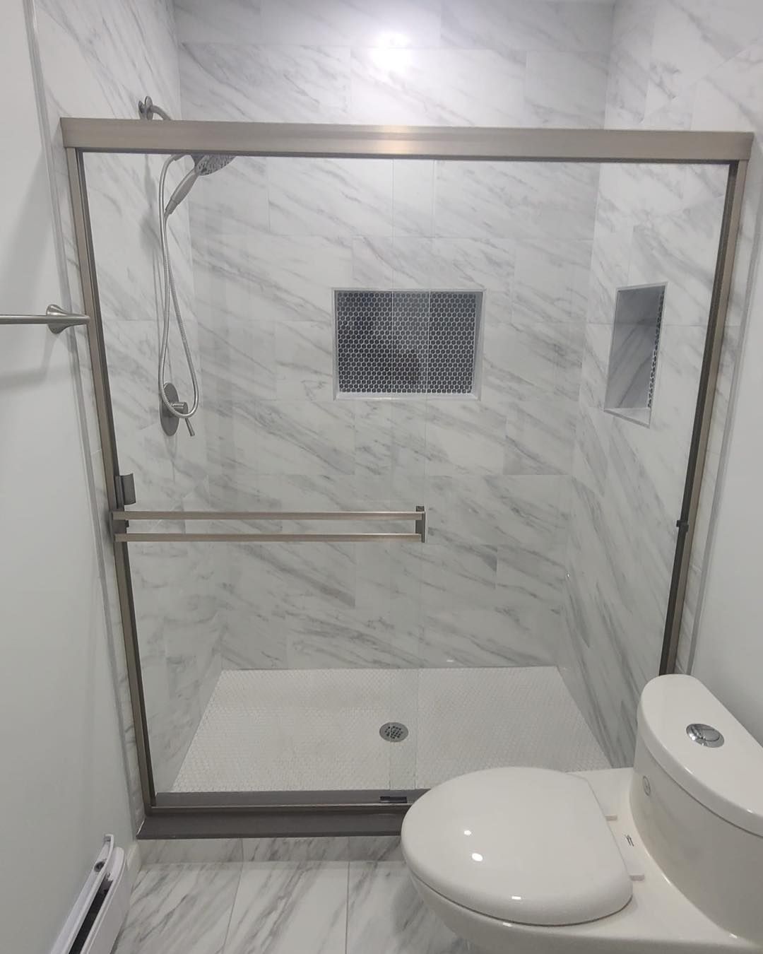 A bathroom with a toilet and a shower with a glass door