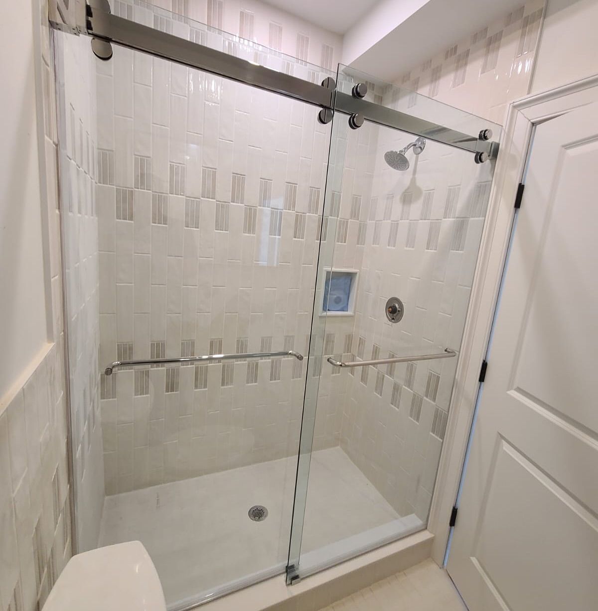 A bathroom with a sliding glass shower door and a toilet.