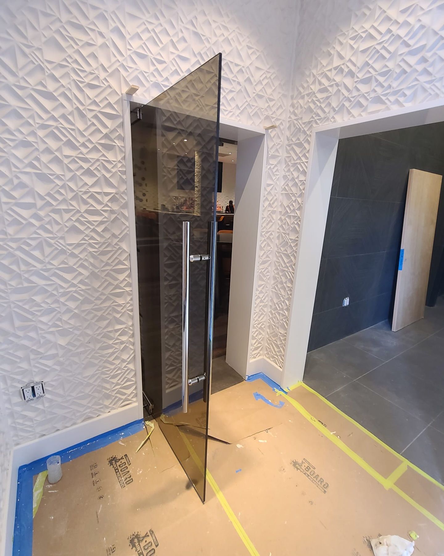 A glass door with a handle is open in a hallway.