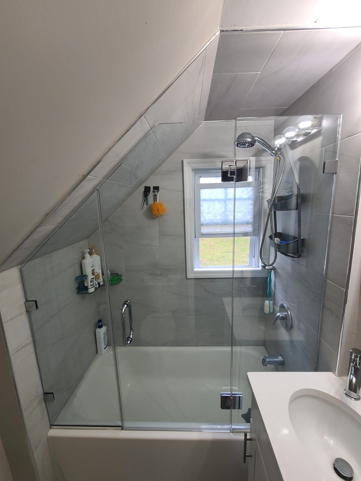 A bathroom with a bathtub , sink , shower and window.