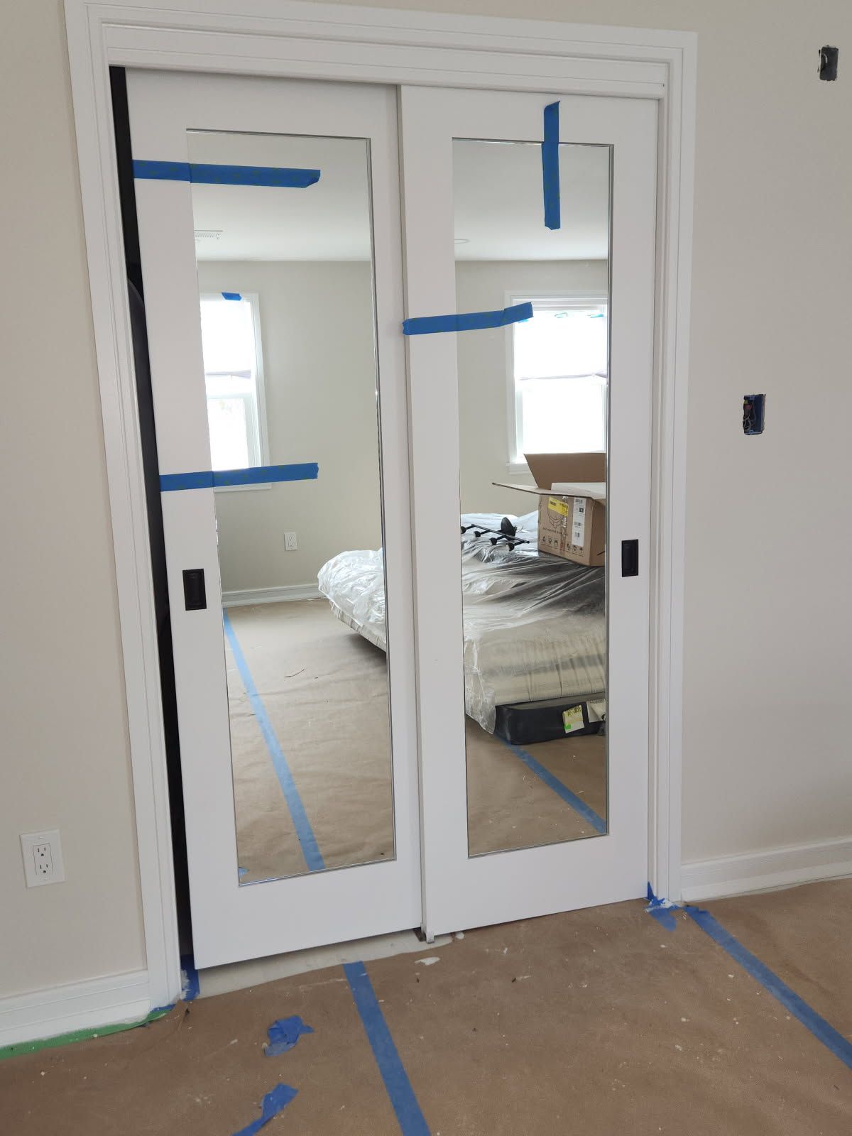 A pair of sliding glass doors with mirrors in a bedroom.