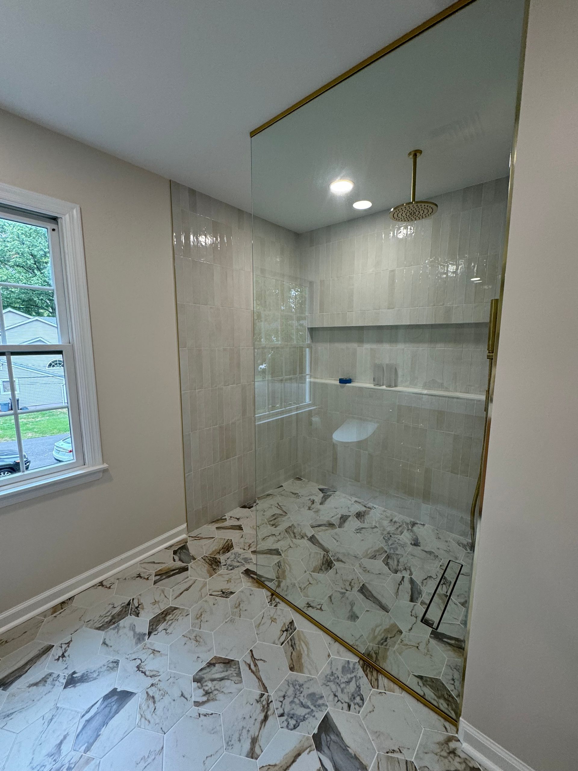 A bathroom with a walk in shower and a window.