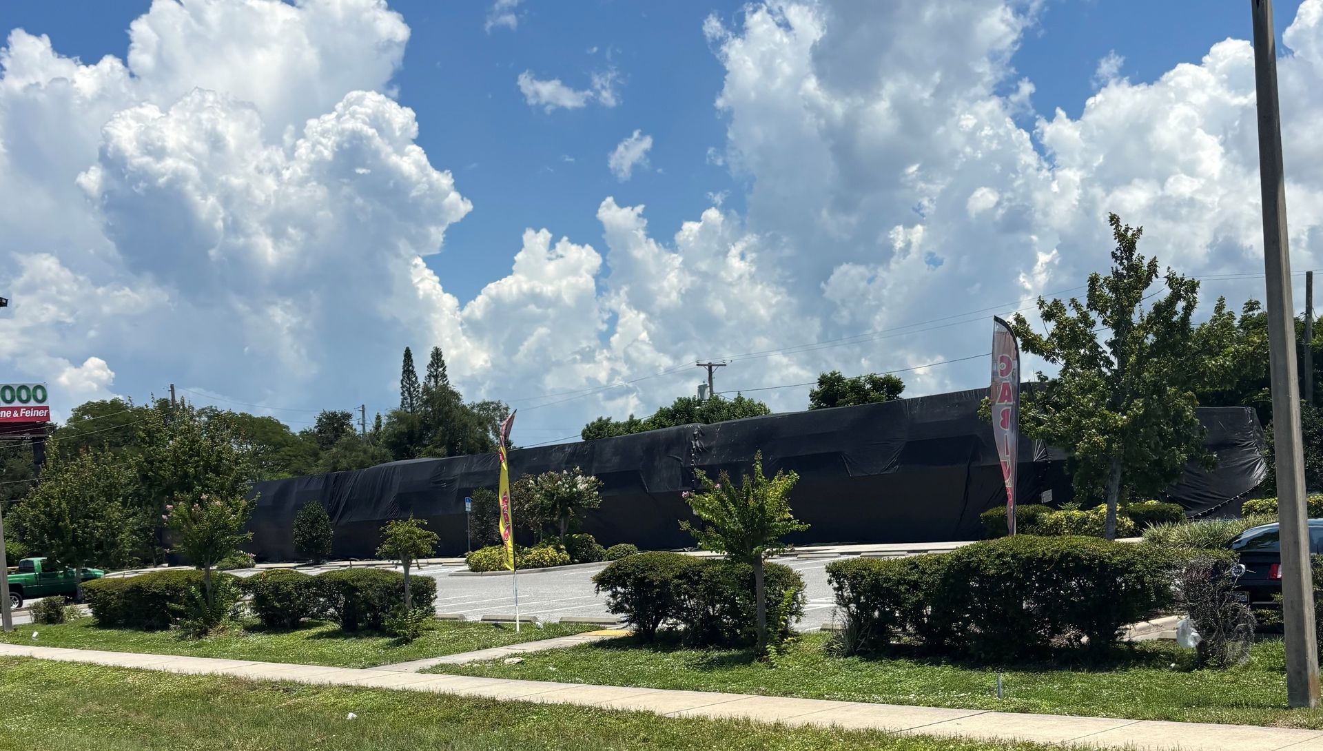 Restaurant building under a cloudy blue sky, with green bushes and trees in front.