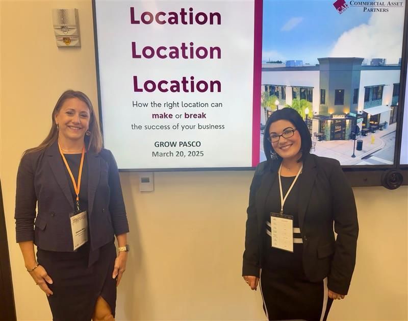 Two women standing in front of a presentation screen that reads 