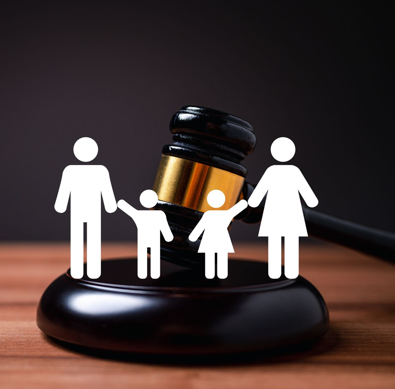 Family silhouettes around a judge’s gavel on a wooden base, symbolizing family law or custody decisions