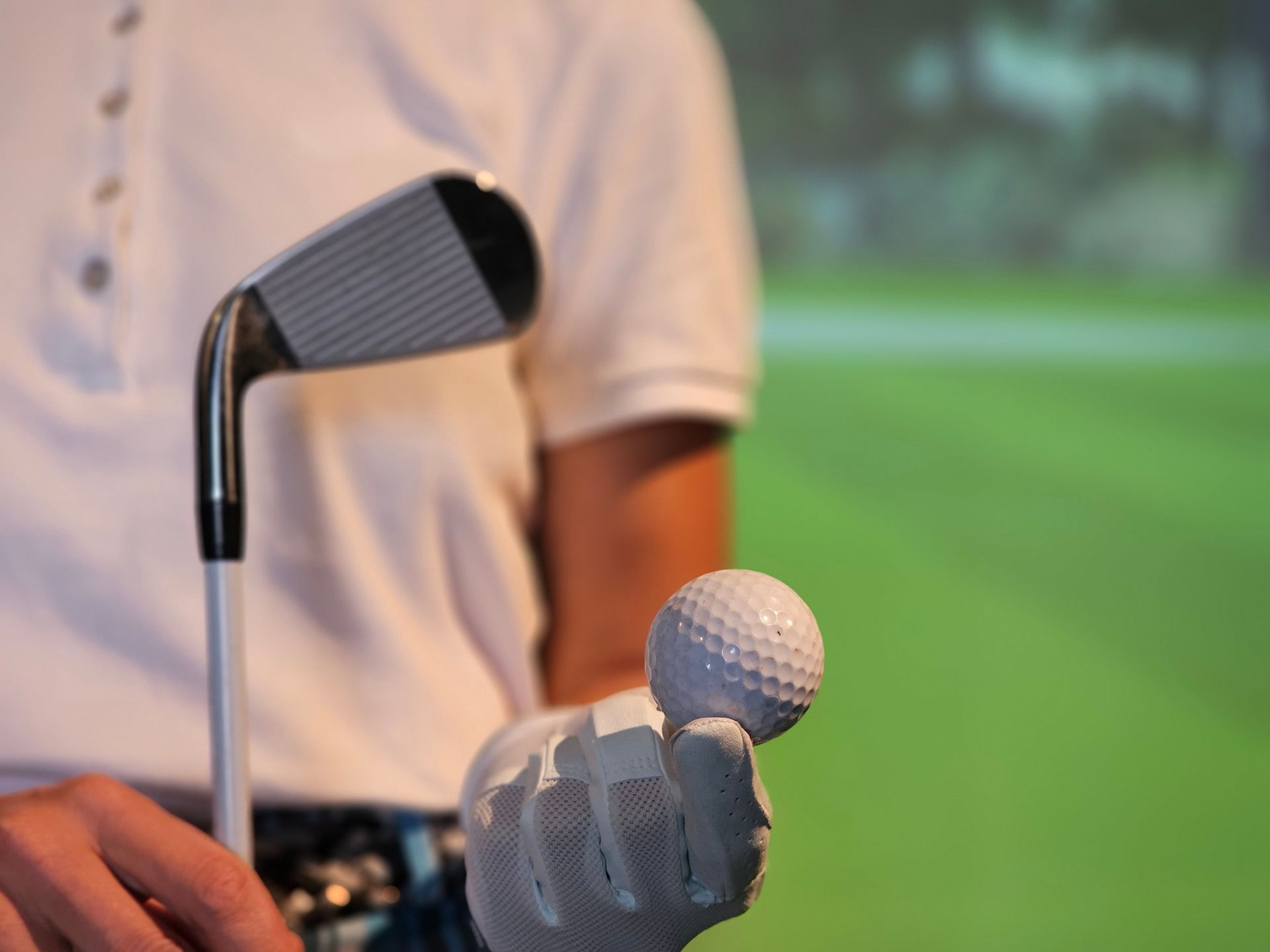 Golfer holding a club and teeing up a ball on a green fairway