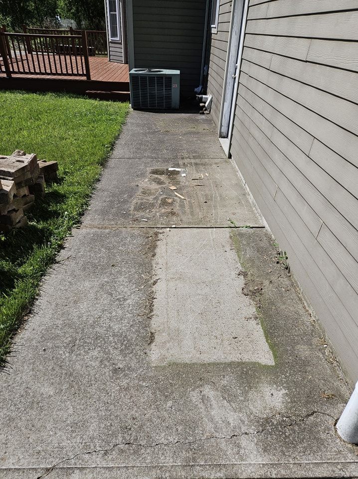 Concrete sidewalk along a house exterior, featuring an area of lighter, patched concrete and an air conditioning unit.