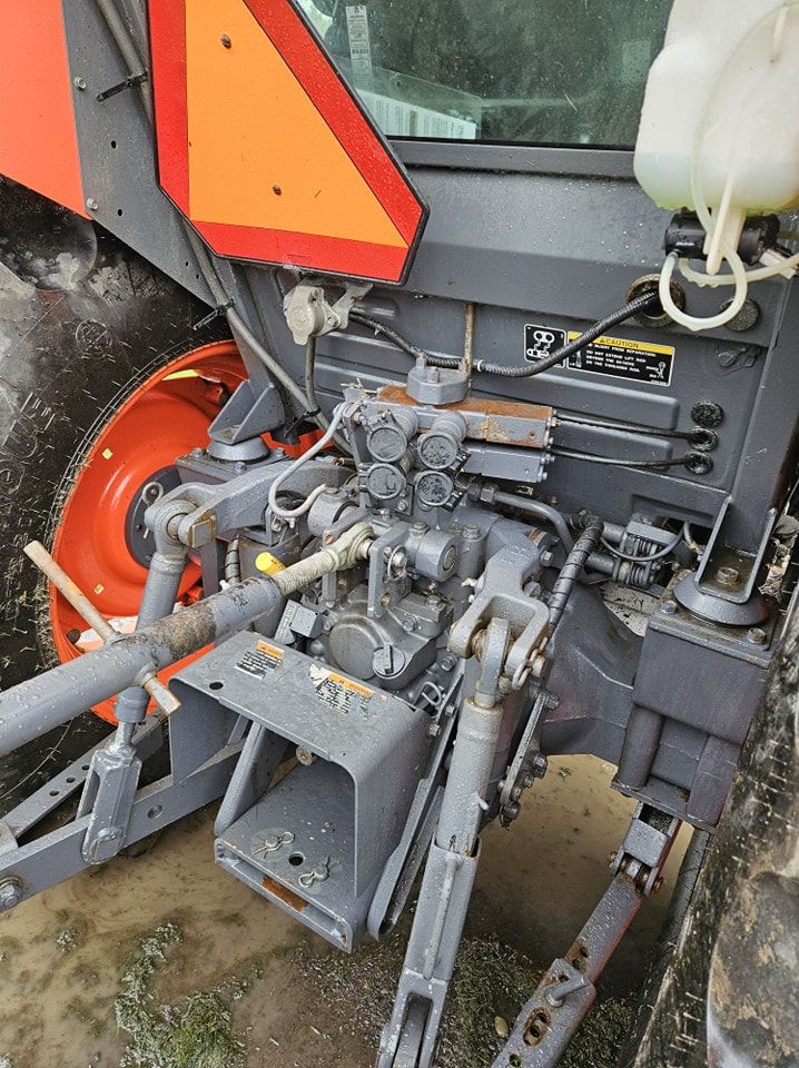 The rear view of an orange and grey tractor showing the three-point hitch, power take-off shaft, and hydraulic ports.