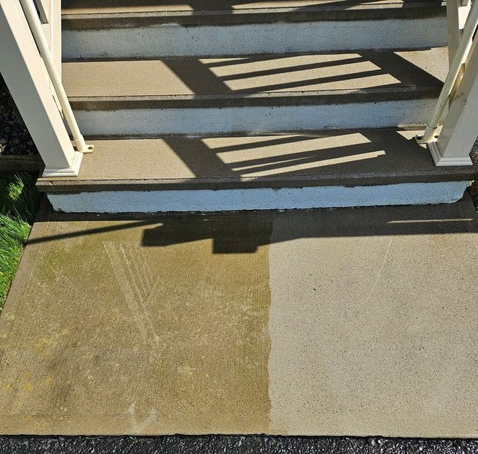 A concrete landing with a visible contrast between a mossy, green-stained section and a newly power-washed, clean section.