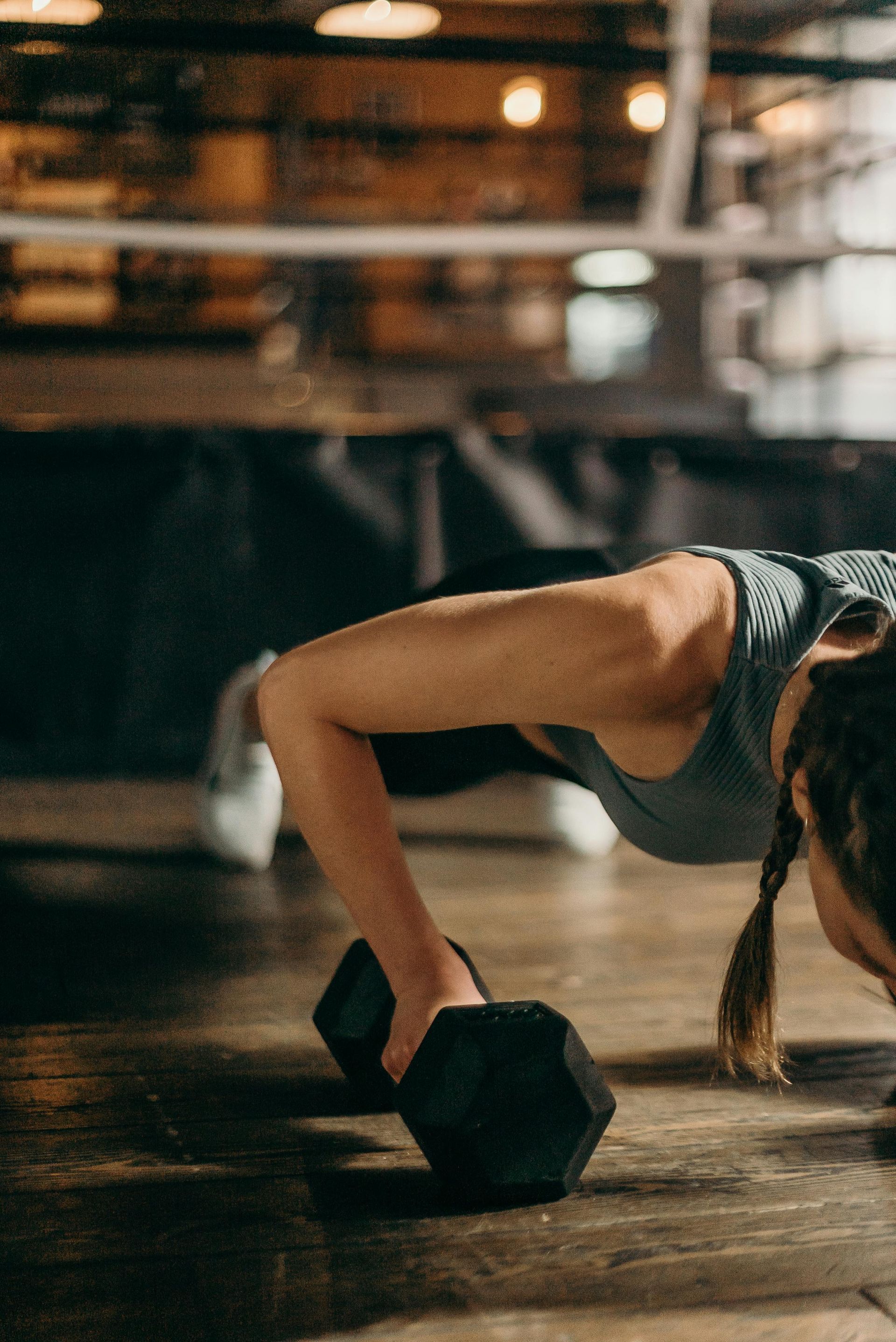 Een vrouw doet push-ups met een halter in een sportschool.