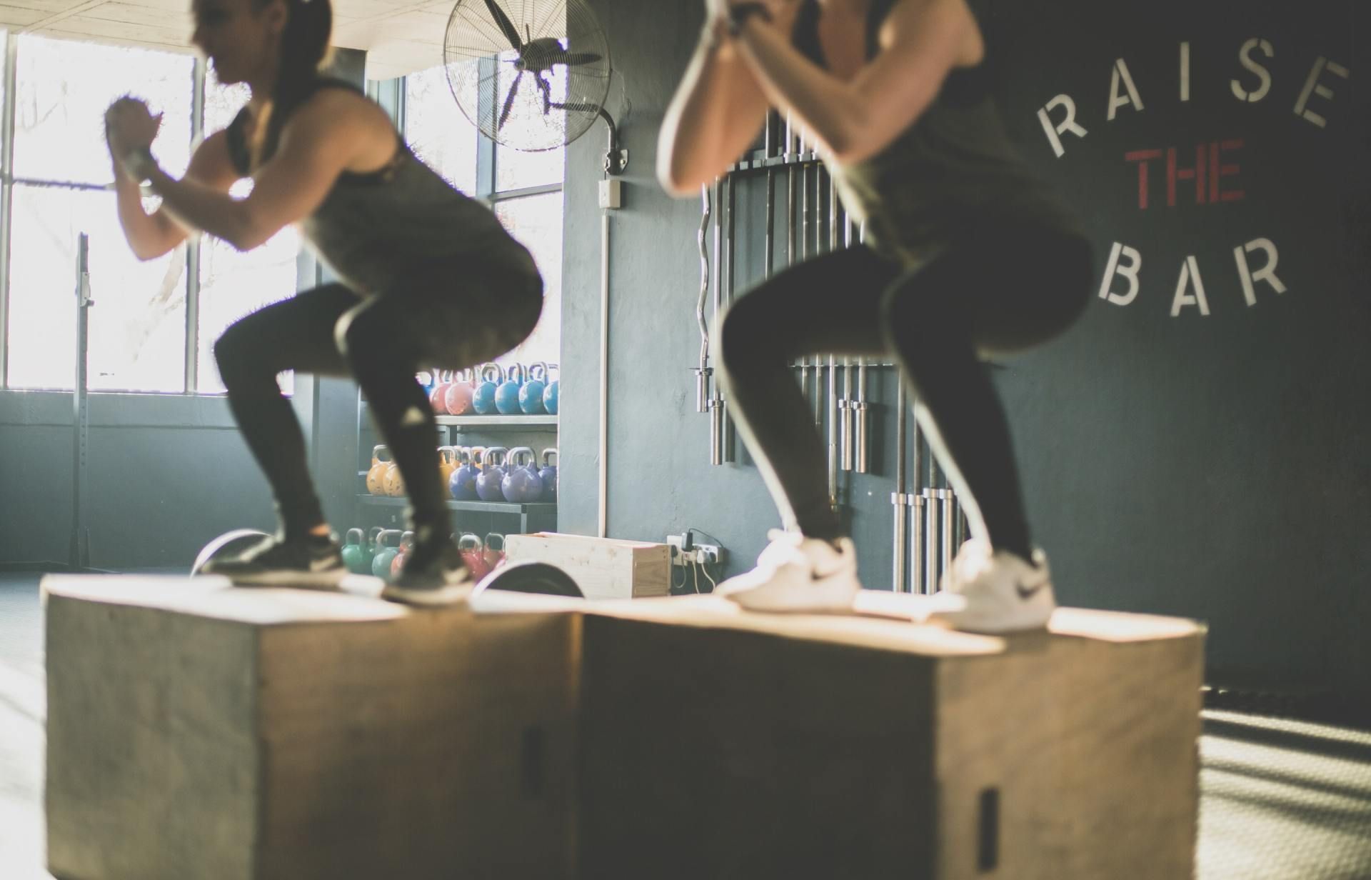 Twee vrouwen hurken op dozen in een sportschool.