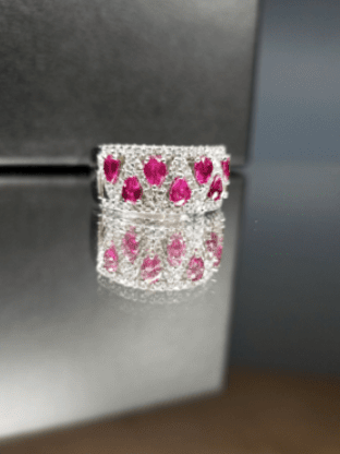 A close up of a ring with pink stones on a table.