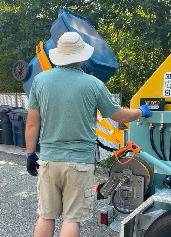 A person is holding a spray bottle over a trash can.