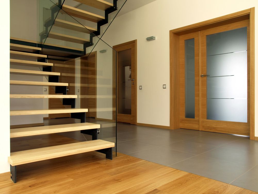 A Wooden Staircase With A Glass Railing In A Hallway — Settle Petal Mobile Conveyancing In Taree, NSW
