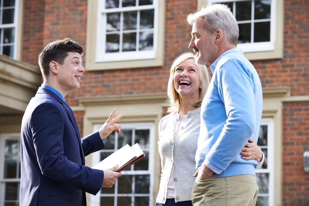 A Man Is Talking To A Couple In Front Of A Brick House — Settle Petal Mobile Conveyancing In Forster, NSW
