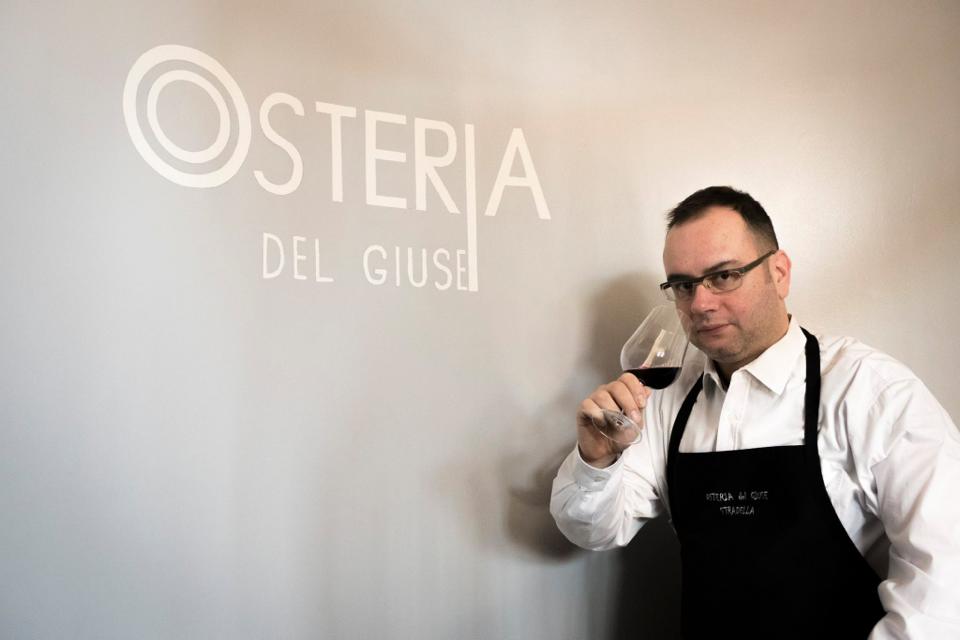 Uomo con grembiule che annusa vino davanti al logo 