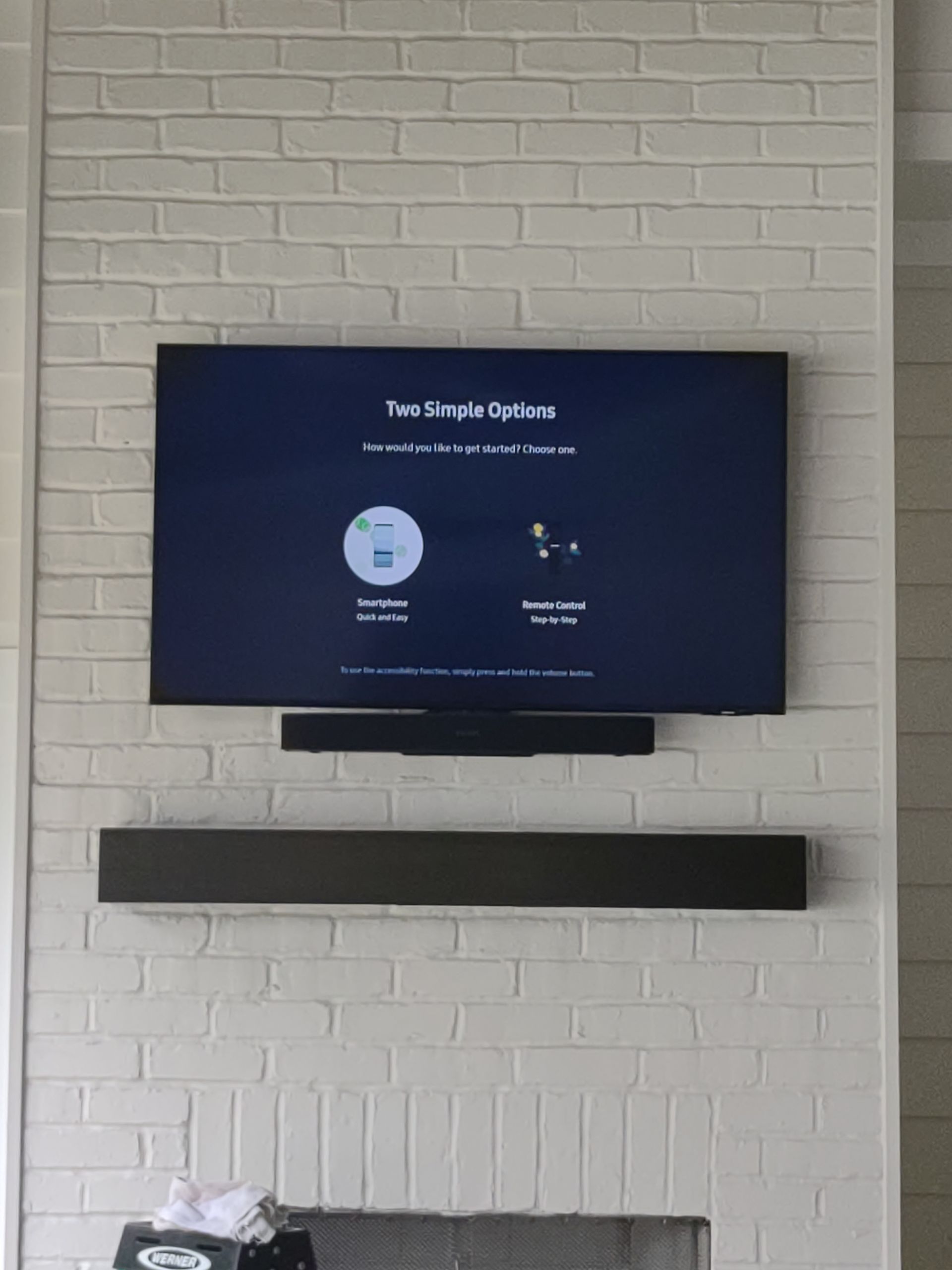 A flat screen tv mounted on a white brick wall