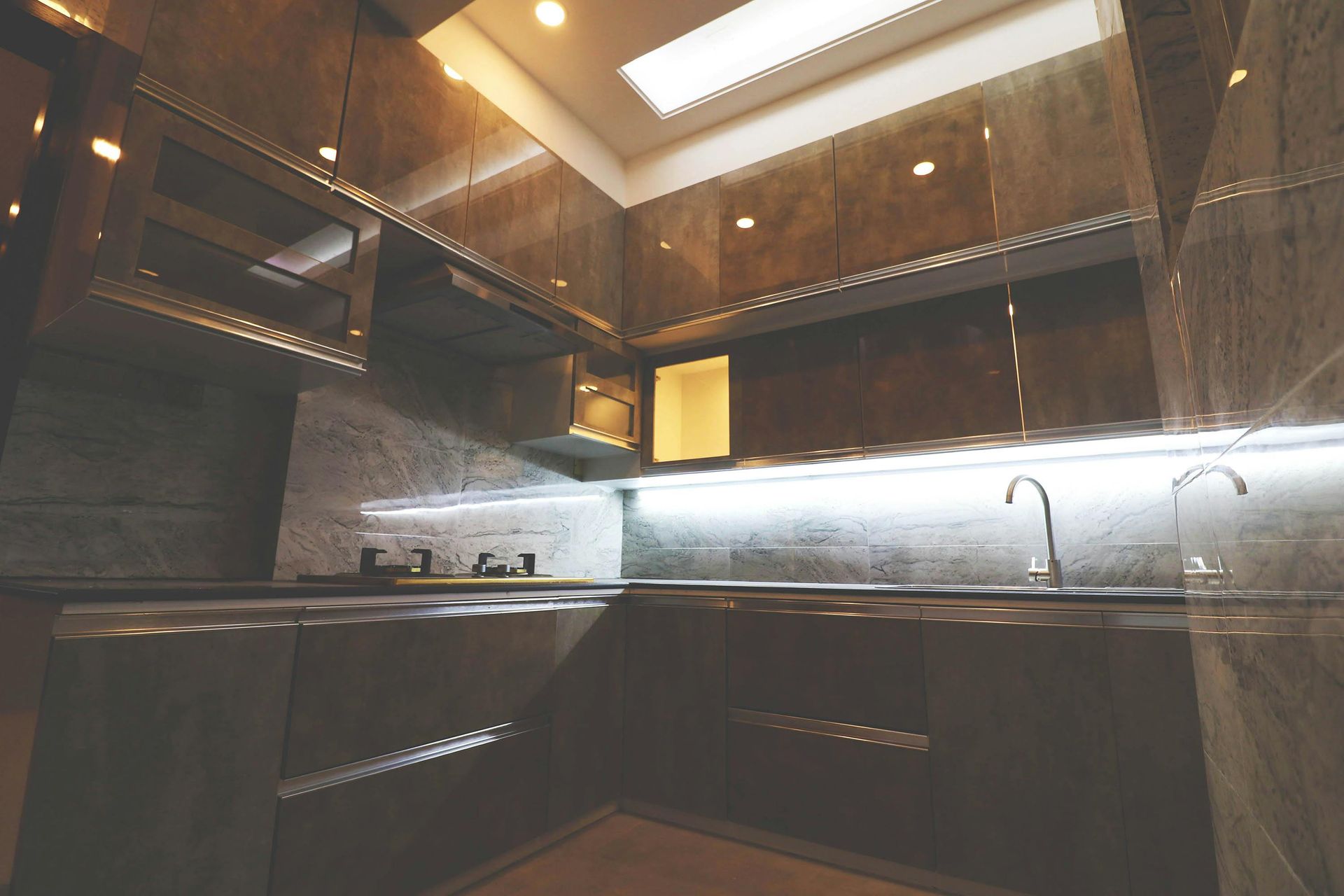 Modern kitchen with dark granite-like surfaces, overhead cabinets, under-cabinet lighting, and a skylight.