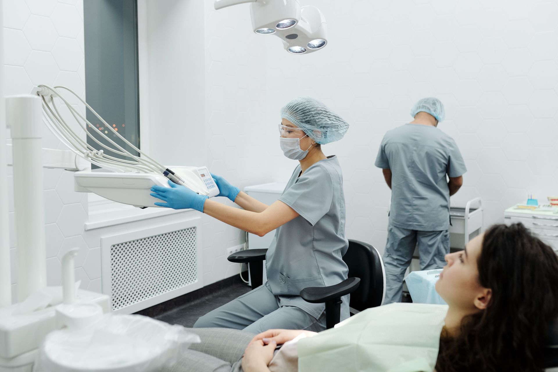 Dentist, dental assistant, and patient all in a room preparing for treatment/procedure