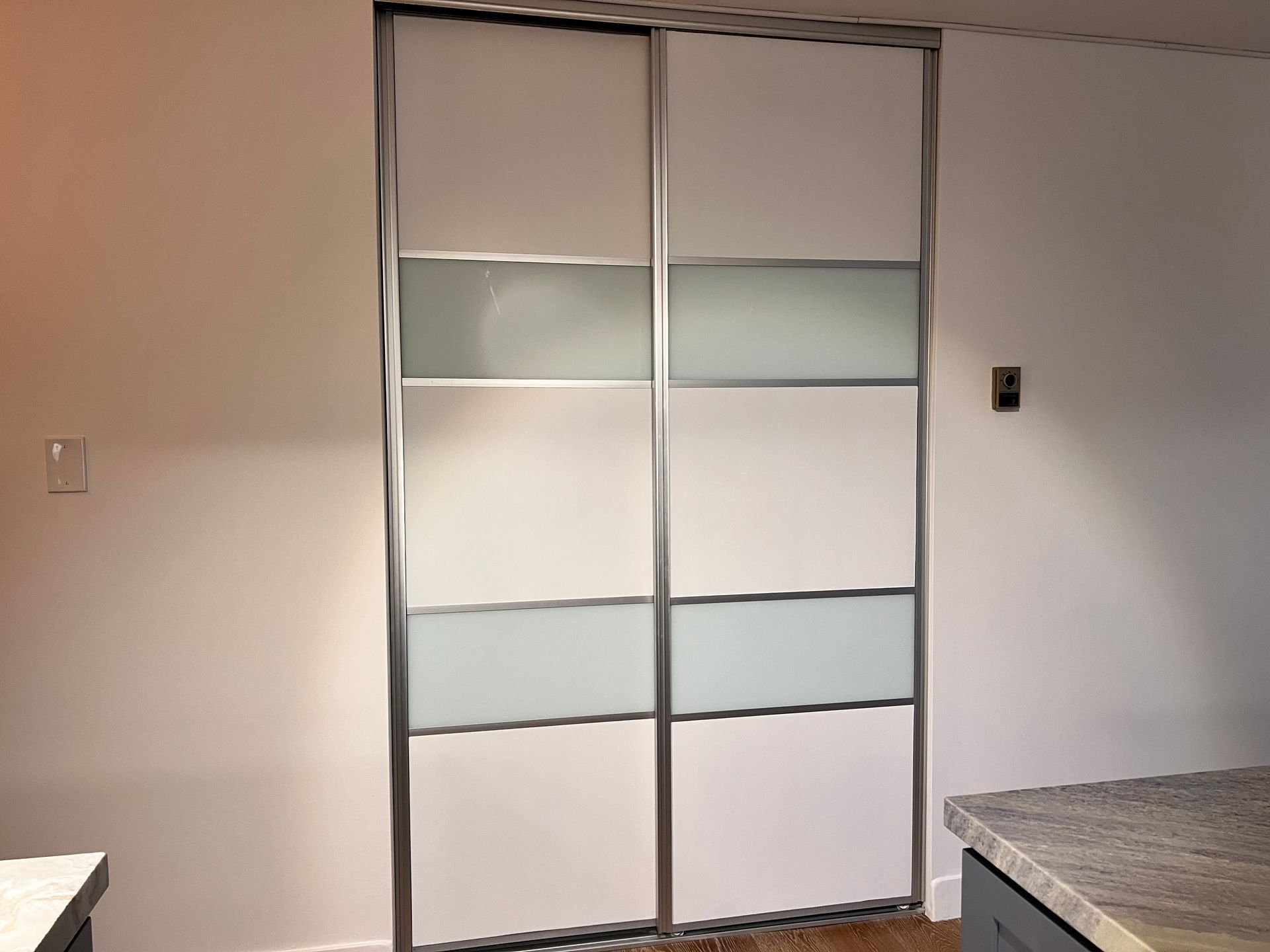 White closet doors with frosted glass panels in a plain room.