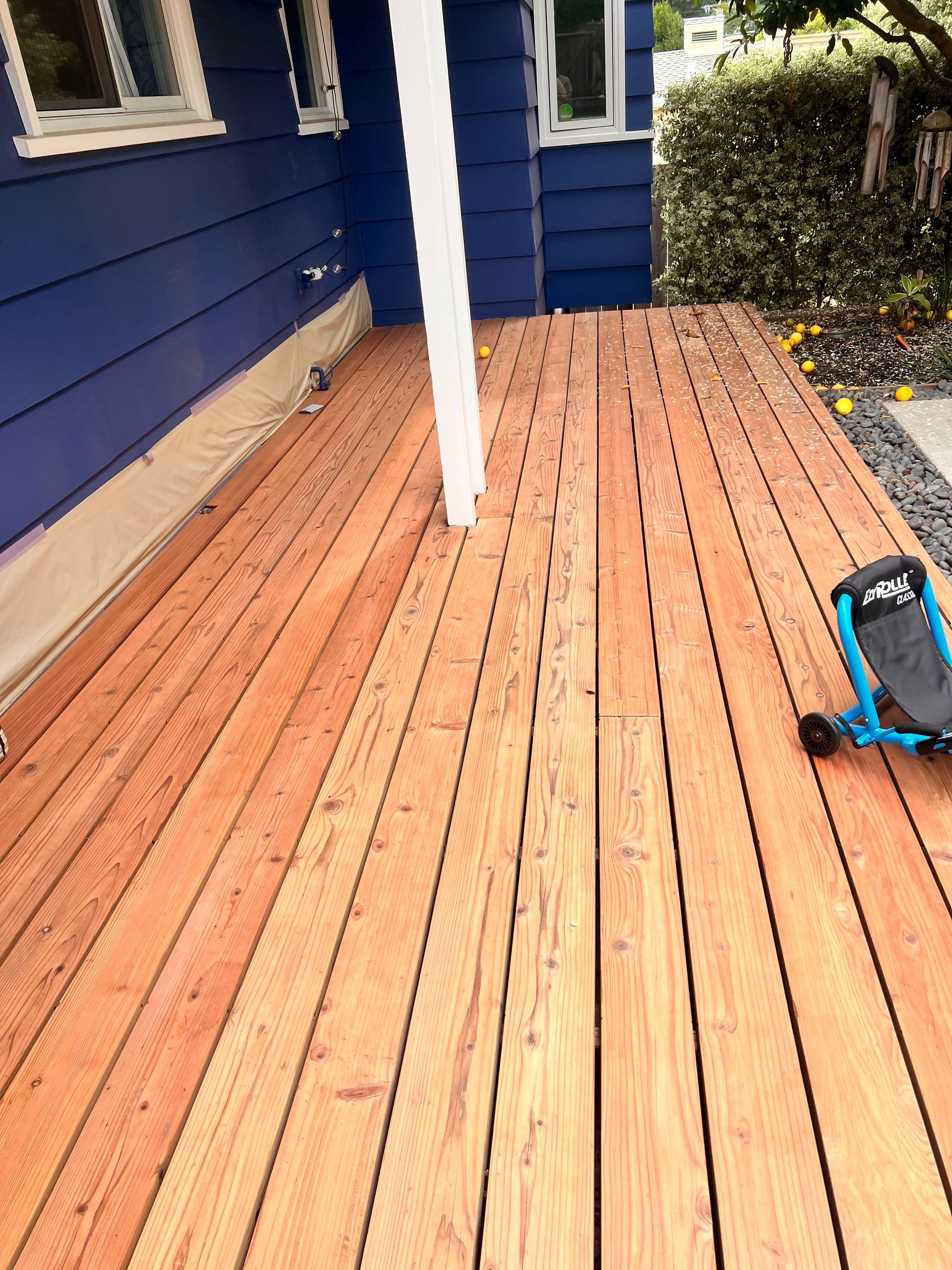 Wooden porch with blue siding and a backpack on the right side.