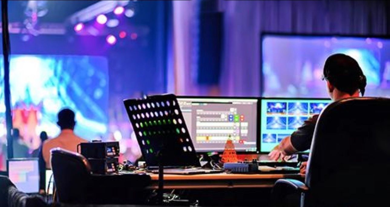 Event production control room with staff at monitors and stage lights in the background