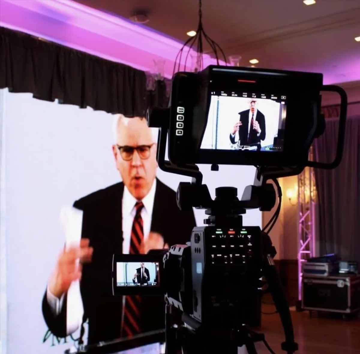 A man in a suit and tie is being recorded on a video camera.