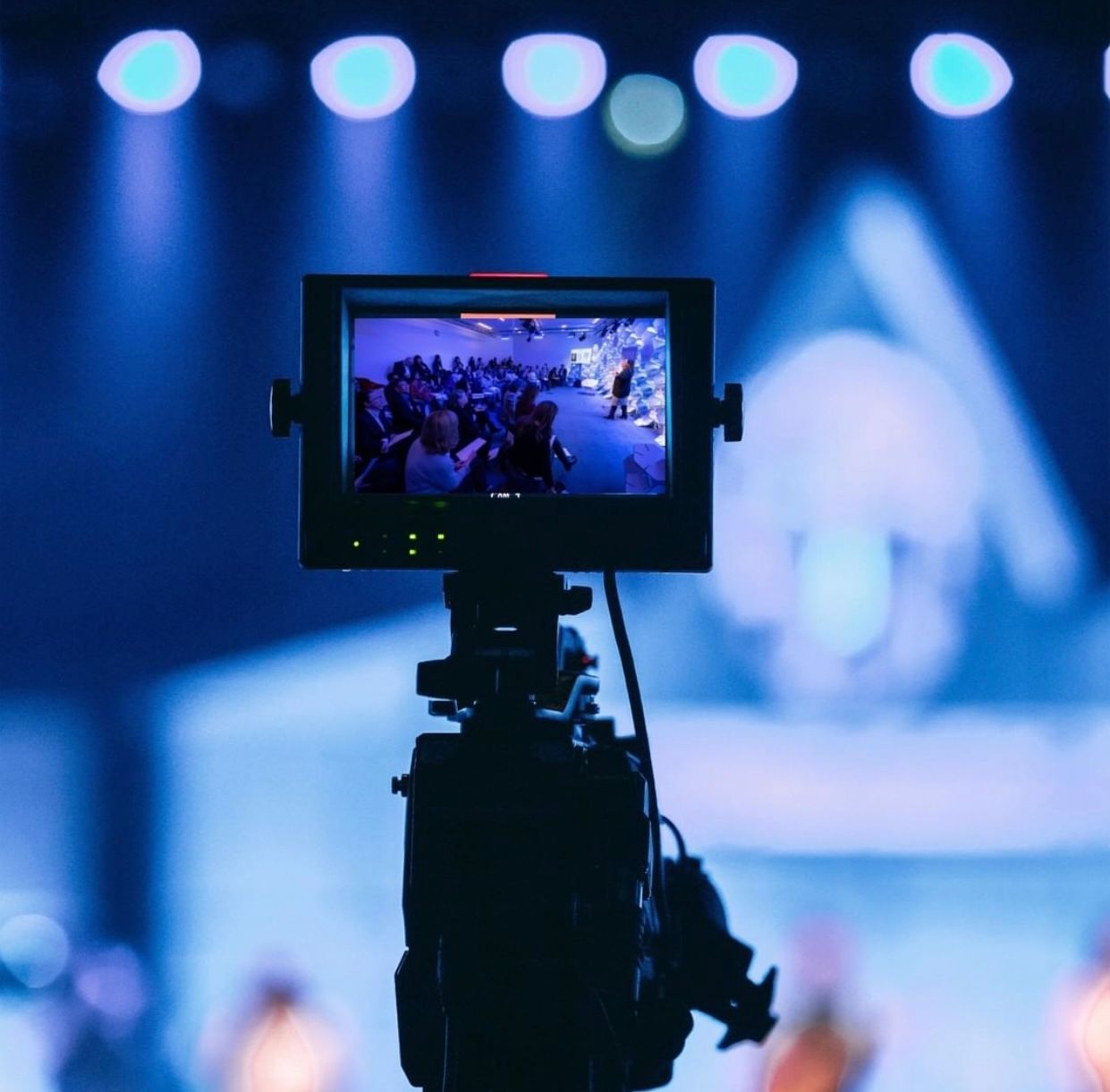 A camera is recording a group of people on a stage.
