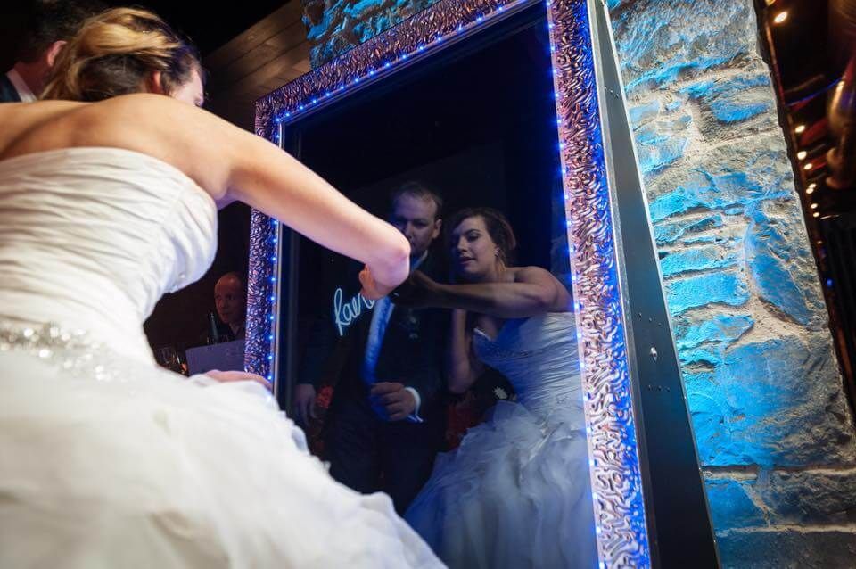 A bride and groom are taking a picture of themselves in a mirror.