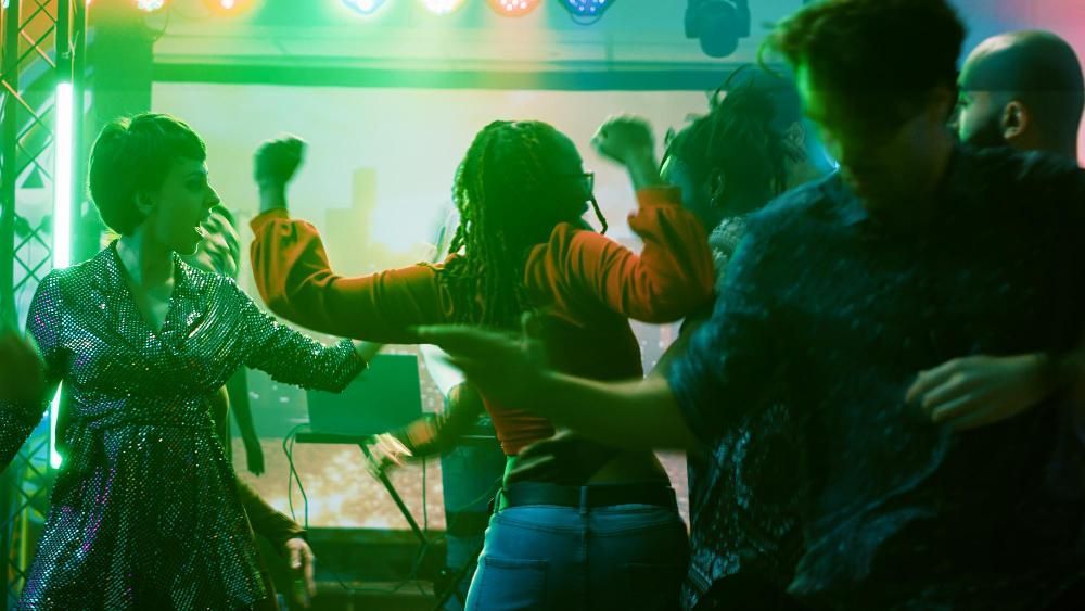 A group of people are dancing on a stage in a club.
