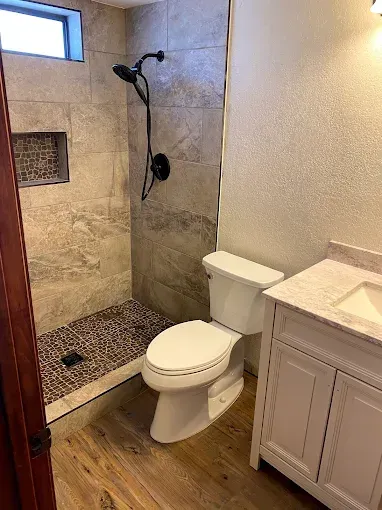 Bathroom with a tiled shower, toilet, and vanity.